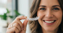 Adult holding a NewSmile aligner, showcasing a discreet teeth straightening solution