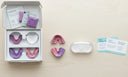 A clean, modern dental flat-lay showing aligner trays, impression kit, aligner case,