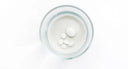 Toothpaste tabs dissolving into a glass of water.