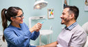 dentist demonstrating gum-care settings on an electric toothbrush.