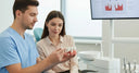 Dentist explaining dental bridge options to a patient with a 3D teeth model