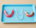 Flatlay of different types of retainers (Hawley, clear, fixed) on a dental tray.
