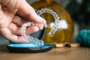 Person holding clear retainers between fingers with close-up focus.