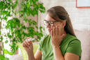 Person holding a clear retainer while touching their jaw in discomfort