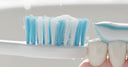 Close-up of a soft-bristle toothbrush brushing along the gumline with gentle foam