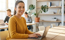 Entrepreneur smiling confidently in a coworking office with laptop.