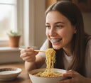 Teen with braces happily eating a bowl of soft noodles.
