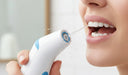Person using a water flosser to clean between teeth and along the gumline