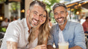 Happy couple smiling at an outdoor cafe with straight teeth from wearing retainers after clear aligner treatment