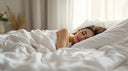 Woman sleeping peacefully in a comfortable white bed wearing a custom night guard to protect her teeth