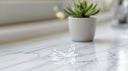 Clear dental retainer on a white surface with a dental case in the background — how much do retainers cost in 2026