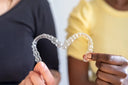 two persons holding a clear aligner
