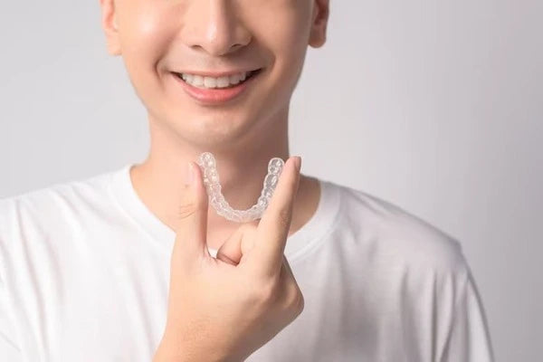 Person holding a clear dental aligner against a plain background