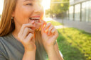 Smiling woman holding a clear retainer – affordable custom clear retainers online.