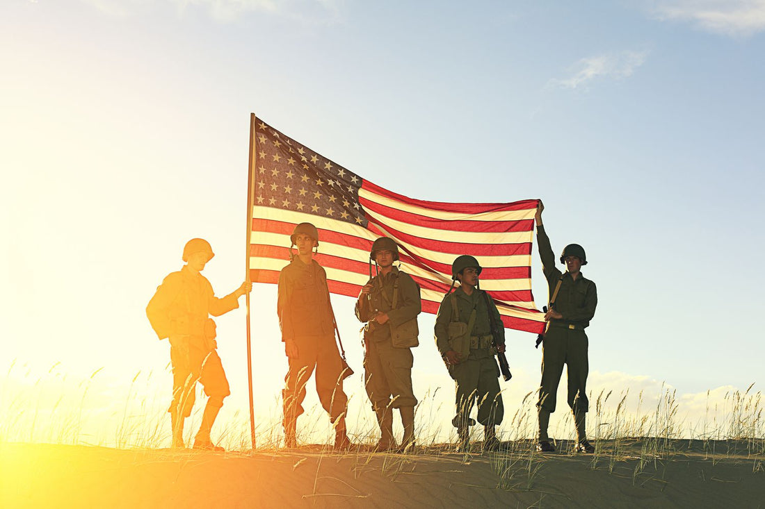 Silhouettes of soldiers holding an American flag against a sunset sky.